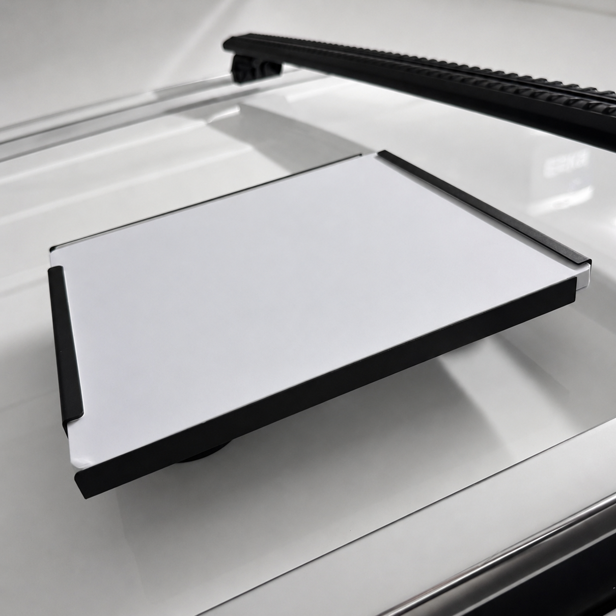 Angled studio-style photo of the Starlink Mini Vehicle Magnet Mount in carbon steel mounted on four 65mm (2.5 inch) magnets on a car roof with a Rhino Rack in the background