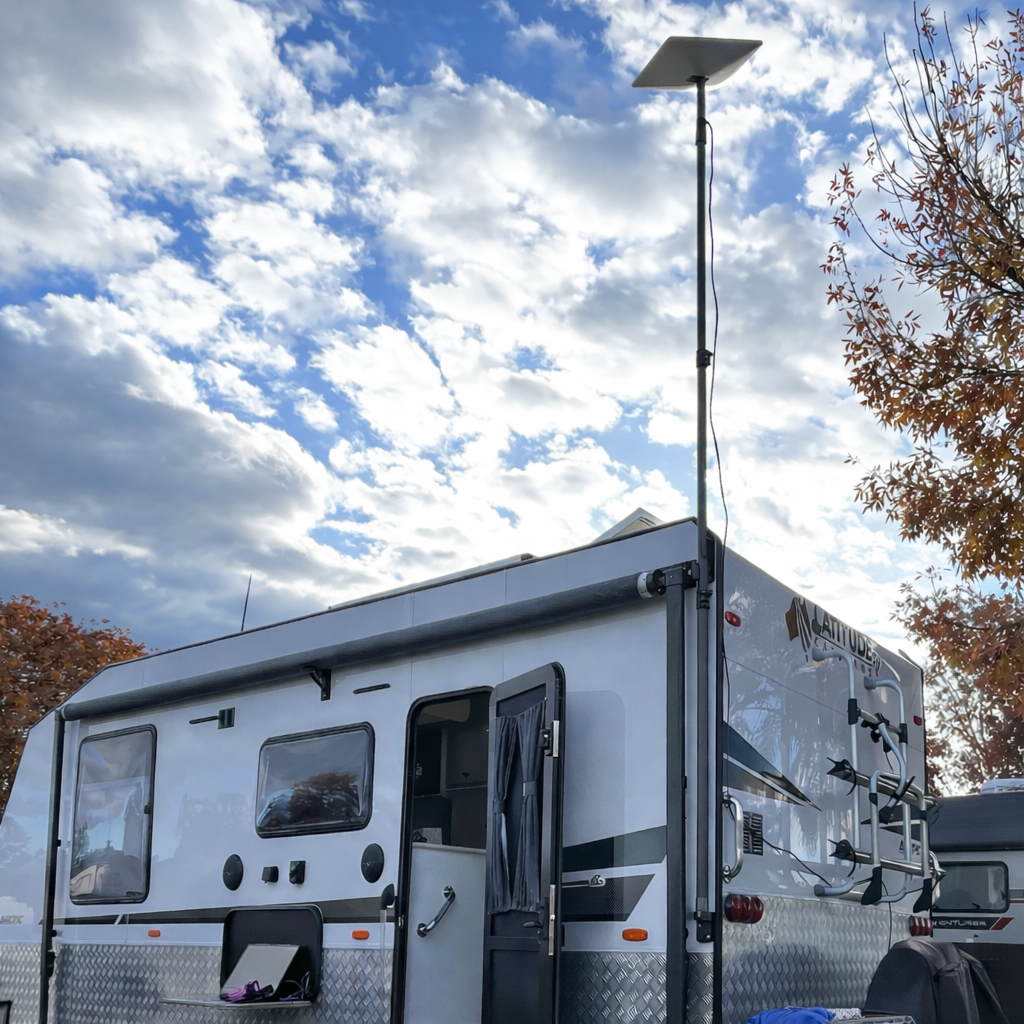 Starlink Gen 2 receiver mounted on Spacetek carbon fibre telescopic pole installed on caravan at campsite with autumn trees. RV satellite internet setup